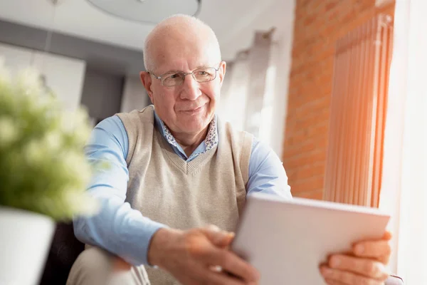 Senior man met digitale tablet in woonkamer — Stockfoto