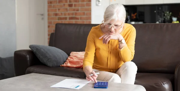 Mujer mayor con calculadora y cuenta facturas —  Fotos de Stock