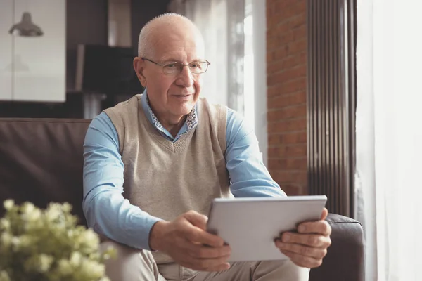 Senior man met digitale tablet in woonkamer — Stockfoto