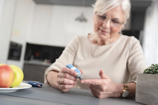 Senior vrouw het controleren van haar bloedsuikerspiegel — Stockfoto