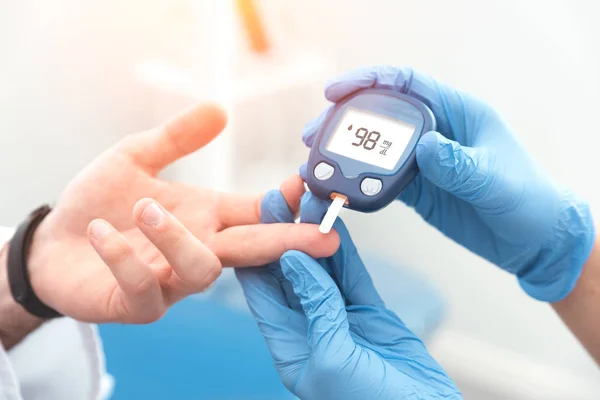 Doktor sprawdzanie poziomu cukru we krwi z glukometrem — Zdjęcie stockowe