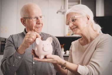 Kıdemli çift piggybank içine sikke koyar
