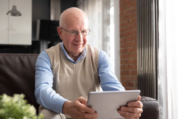 Senior man met digitale tablet in woonkamer — Stockfoto