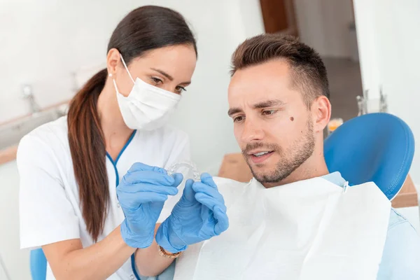 Zahnarzt zeigt unsichtbare Zahnspange — Stockfoto