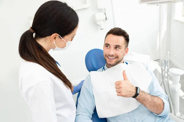 Young doctor dentist and patient showing thumb up — Stock Photo, Image