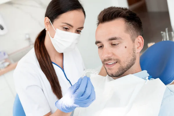 Zahnarzt zeigt unsichtbare Zahnspange — Stockfoto