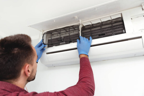 Technician replacing filter in air conditioner