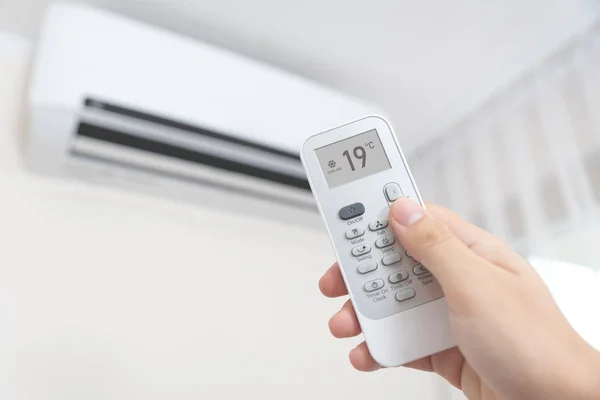 Hand with remote directed on air conditioner. — Stock Photo, Image