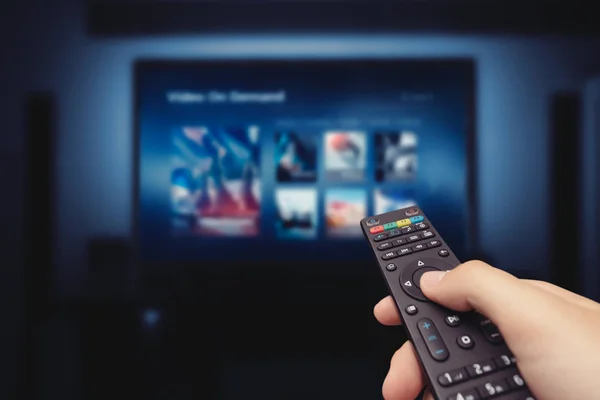 VOD service screen with remote control in hand — Stock Photo, Image