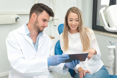 Klinikte diş muayenesi. Diş hekimi dijital tablet ekranda diş röntgeni gösteriyor