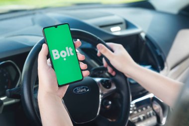 Wroclaw, Poland - AUG 25, 2020: Bolt driver holding smartphone in car. Bolt is sharing-economy service for ubran transport. clipart
