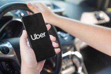 Wroclaw, Polonya - 25 AUG 2020: Uber sürücüsü akıllı telefonu arabada tutuyor. Uber ubran taşımacılığı için ekonomi hizmetini paylaşıyor.
