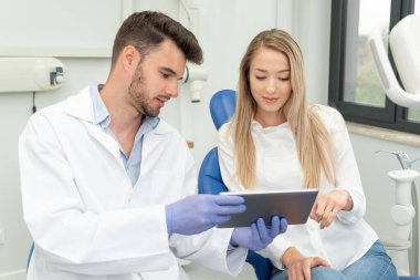 Klinikte diş muayenesi. Diş hekimi dijital tablet ekranda diş röntgeni gösteriyor