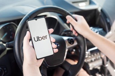 Wroclaw, Polonya - 25 AUG 2020: Uber sürücüsü akıllı telefonu arabada tutuyor. Uber ubran taşımacılığı için ekonomi hizmetini paylaşıyor.