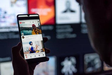 Wroclaw, Polonya - SEP 16, 2020: YouTube uygulaması olan akıllı telefonu ekranda tutan adam. YouTube, Google tarafından geliştirilen en popüler video servisidir..