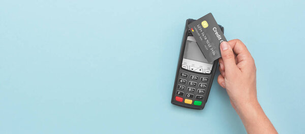 Credit card payment terminal. Man using credit card. Wide image with copy space and blue background
