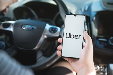 Wroclaw, Polonya - 25 AUG 2020: Uber sürücüsü akıllı telefonu arabada tutuyor. Uber ubran taşımacılığı için ekonomi hizmetini paylaşıyor.
