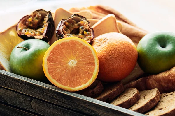 Various of fruit and bread such as orange, apple placing together in wooden box; sweet and delicious ingredient