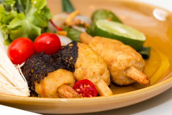 Close up of crispy shrimp wrapped with sugar cane decorated by tomato and vegetable