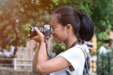 Sırt çantalı güzel Asyalı kadınlar sıcak ışık altında ormanda kameraya nişan alırlar.