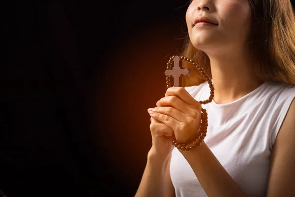 Kadın siyah arka planda Cross ile Tanrı 'ya dua eder; kadın daha iyi bir hayat dilemek için Tanrı' ya dua eder.