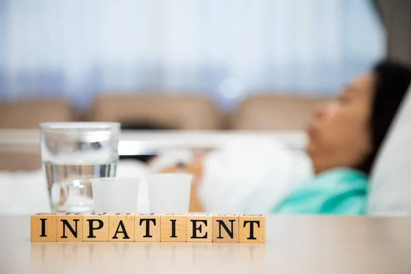 Female patient sleeping in hospital patient room with Inpatient wording block on table