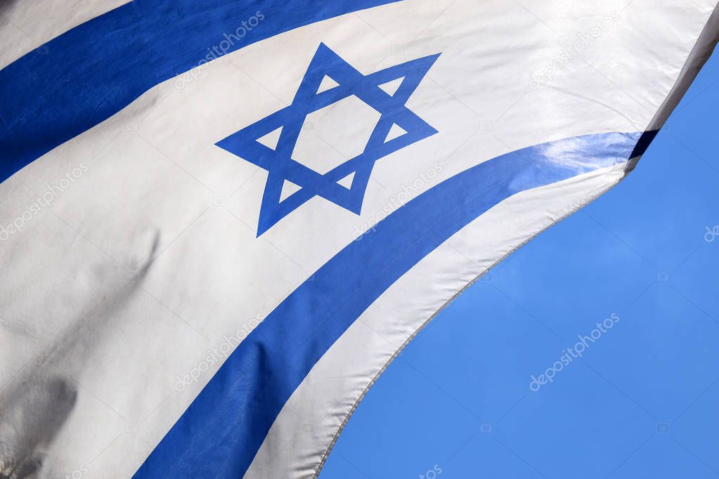 Star of David on a blue and white israeli flag against a bright sky