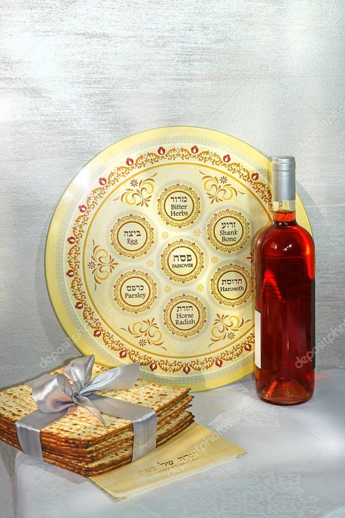 spring holiday of Passover and its attributes, with bottle of wine, seder plate, matzo and Haggadah in Hebrew - Happy Passover