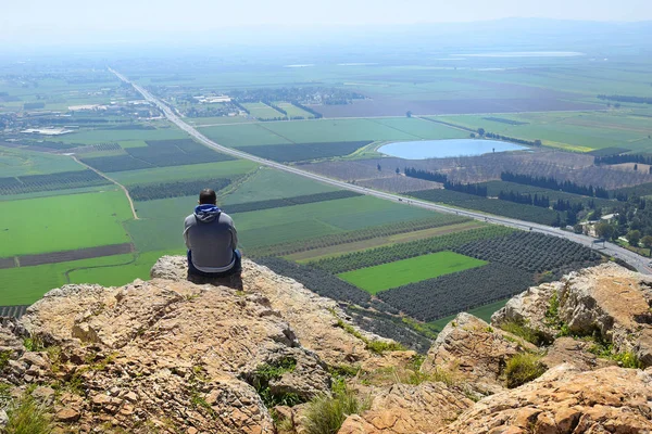 孤独的人坐在悬崖边 看着以色列下加利利拿撒勒附近的耶斯列山谷的壮丽景色 — 图库照片