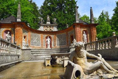 Salzburg, Avusturya - 25 Mayıs 2019 : Salzburg'daki Hellbrunn Sarayı'nın (Schloss Hellbrunn) Halk Bahçeleri'ndeki gölette bir yemek masasına gizlenmiş hileli çeşmeler ve heykeller
