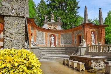 Salzburg, Avusturya - 25 Mayıs 2019 : Salzburg'daki Hellbrunn Sarayı'nın (Schloss Hellbrunn) Halk Bahçeleri'ndeki gölette bir yemek masasına gizlenmiş hileli çeşmeler ve heykeller
