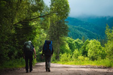 İki arkadaş sırt çantaları ile dağlarda seyahat