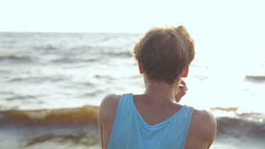 Erkek gömlek ve mızıka sahilde oynarken güneş gözlüğü. Arkadan görüntülemek.