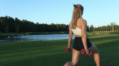 Kadının yapması Sit up parkta dumbbells ile egzersiz.