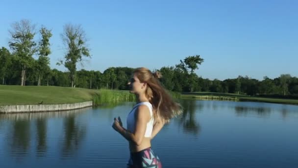 公園の湖の近く走っているスポーティな女性の肖像画 — ストック動画