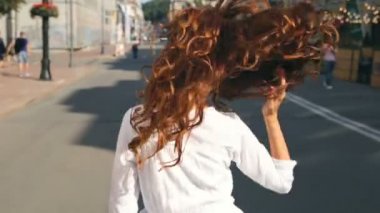Kıvırcık saçlı kadın kulaklık, beyaz elbise zevk iyi günler ile yürüme, eğleniyor.