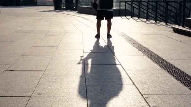 年轻男子背包和滑板站在街上 从后面查看 — 图库视频影像