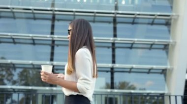 Fincan kahve ve usinf smartphone tutan yürüyüş iş kadın.