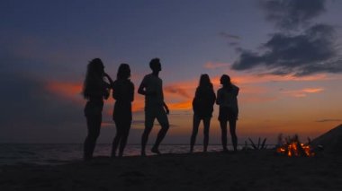 Paty kıyamete. Silhouttes şenlik yakınındaki plajda durup arkadaş. Ağır çekim.