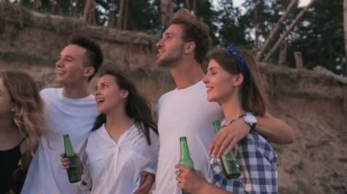 Sahilde duran ve günbatımı zaman zevk mutlu, gülümseyen arkadaşlar.