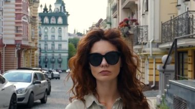 Biraz üzgün, ciddi görünümlü kadın sokakta ayakta ve kameraya bakarak sunglassse. Ağır çekim.