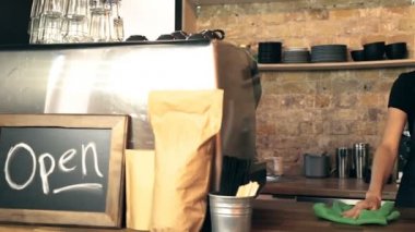 Kadın barista prepearing İşyeri ve Temizleme işlemi toz gülümseyerek. Steadycam atış.