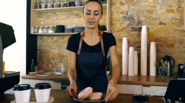 Çörek ve iki bardak kahve müşteriye veren kadın garson. Kahve dükkanı. Ağır çekim.