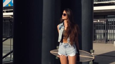 Mutlu, gülümseyen genç kadın. Caddesi ve holding longboard arkadan ayakta.