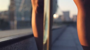 Yakın çekim. Genç kadın ayakta, longboard holding ve city adlı arıyorum. Günbatımı zamanı. Steadycam atış.