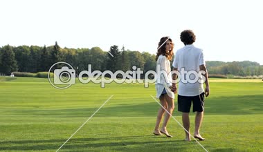 Mutlu çift açık havada parkta yeşil çimenlerin üzerinde yürüyüş. Steadycam atış.