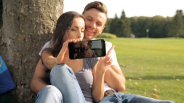 Selfies üstünde smartphone alarak genç mutlu çiftin yakın çekim portre. Park açık havada. Yhe smartphone üzerinde odaklanmak.