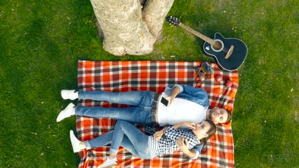 Gelukkige Paar Liggend Plaid Het Park Vriendje Holding Smartphone Luisteren — Stockvideo