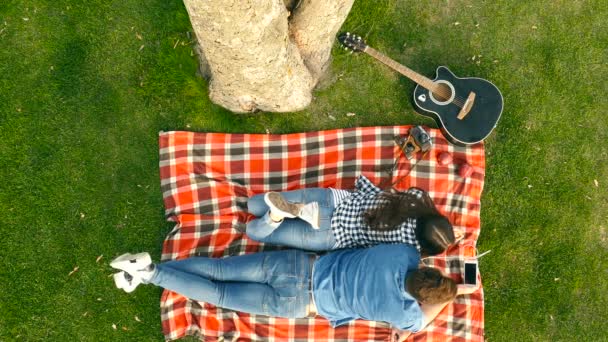 Casal Feliz Deitado Xadrez Parque Namorado Segurando Smartphone Eles Ouvem — Vídeo de Stock