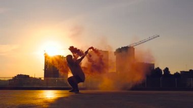 Genç adam tutarak renkli duman ve backflip sommersault hile yaparak. Slowmotion.